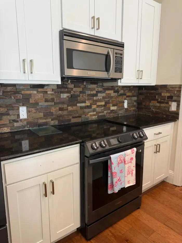 Remodeled kitchen with stone backsplash and new appliances by RGS General Contracting