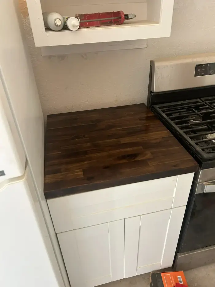 Stained butcher-block counter beside a gas range by RGS General Contracting